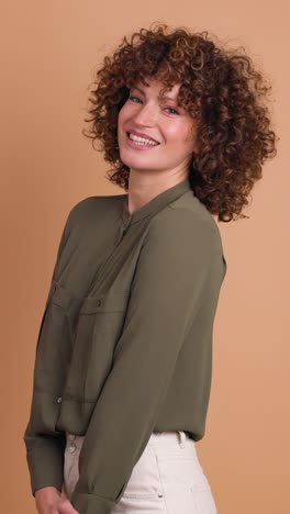 smiling standing young curly haired woman on beige background. vertical orientation
