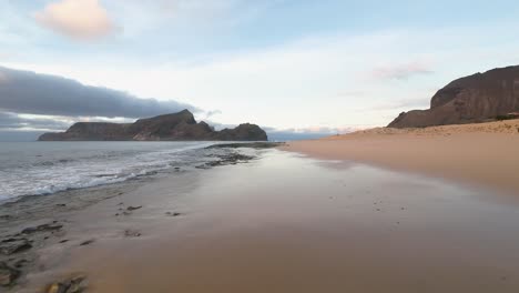 porto santo beach and cliffs reflect on wet sand