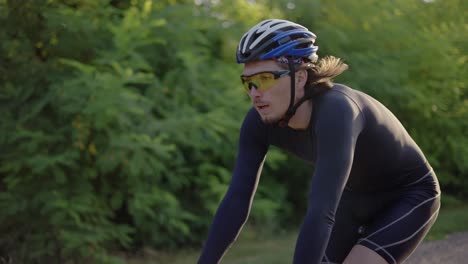 Male-cyclist-in-helmet-rides-bicycle-along-and-empty-track,-Close-Up