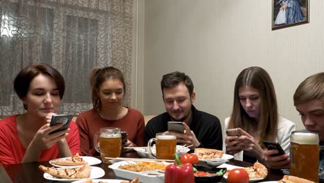 friends enjoying pizza and drinks with mobile phones