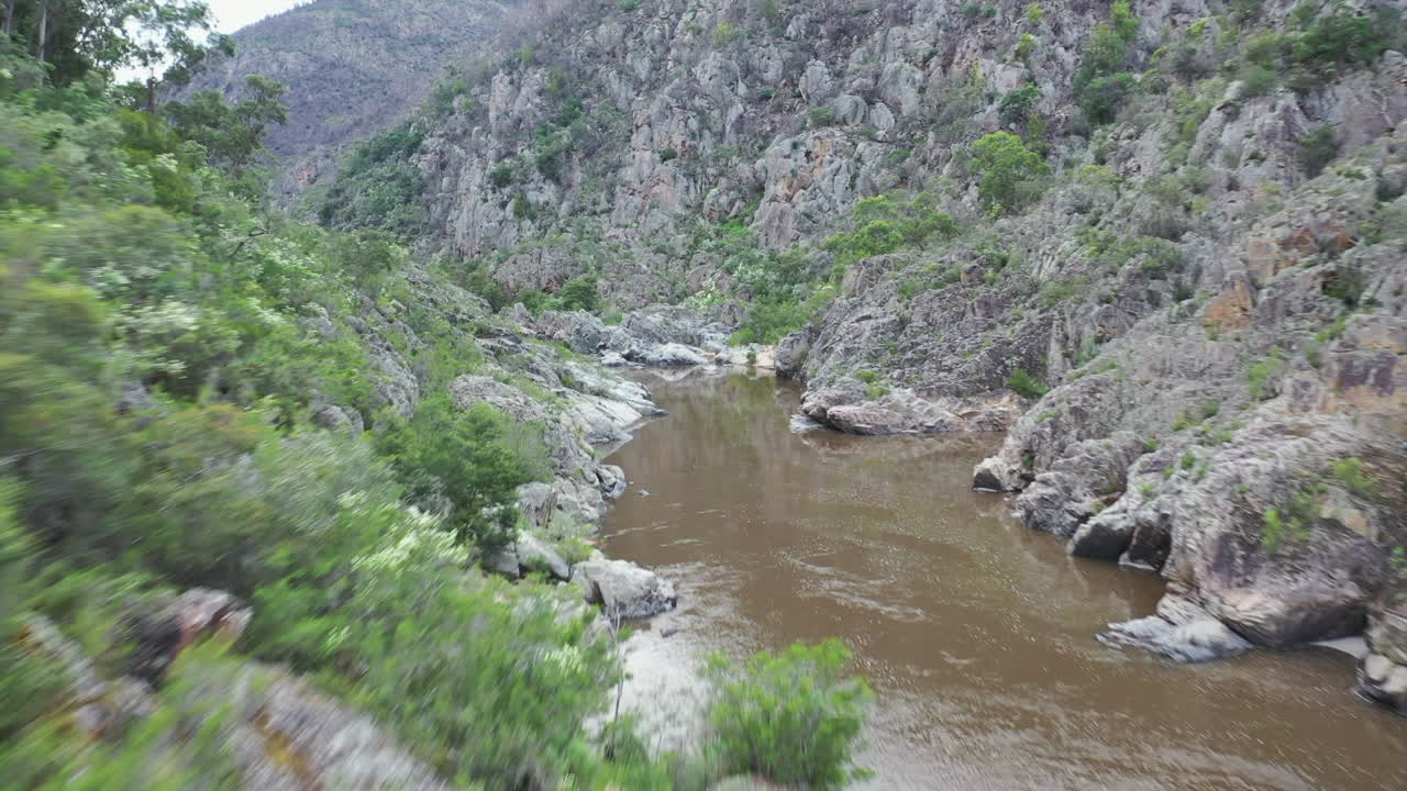 pov vuelo bajo río abajo en el cañón del río remoto hasta el campamento a la derecha