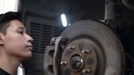 Slow-motion-shot-of-a-mechanic-checking-a-car's-brakes-and-rotors