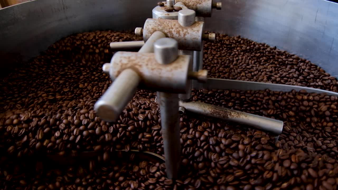 Close up of aromatic, fragrant golden brown coffee beans freshly roasted in industrial coffee roaster