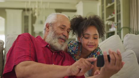 grandfather and granddaughter using smartphone at home