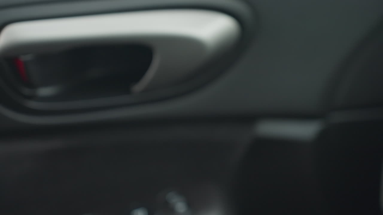 close up fair skinned person hand gripping and pulling car door handle to open car door then releasing handle as door swings closed showing interior texture under soft natural daylight