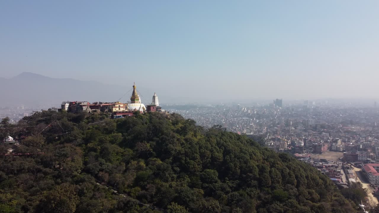 una vista de la estupa swayambhunath en la cima de una colina con la ciudad de katmandú, nepal y las montañas del himalaya en el fondo