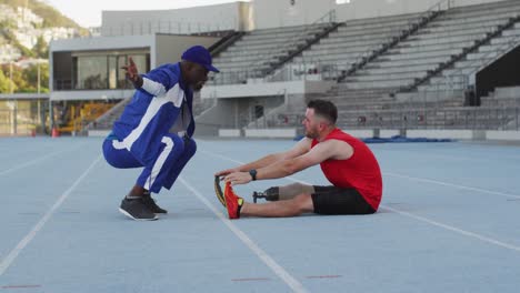 entrenador masculino diverso y atleta discapacitado con entrenamiento y estiramiento de piernas protésicas