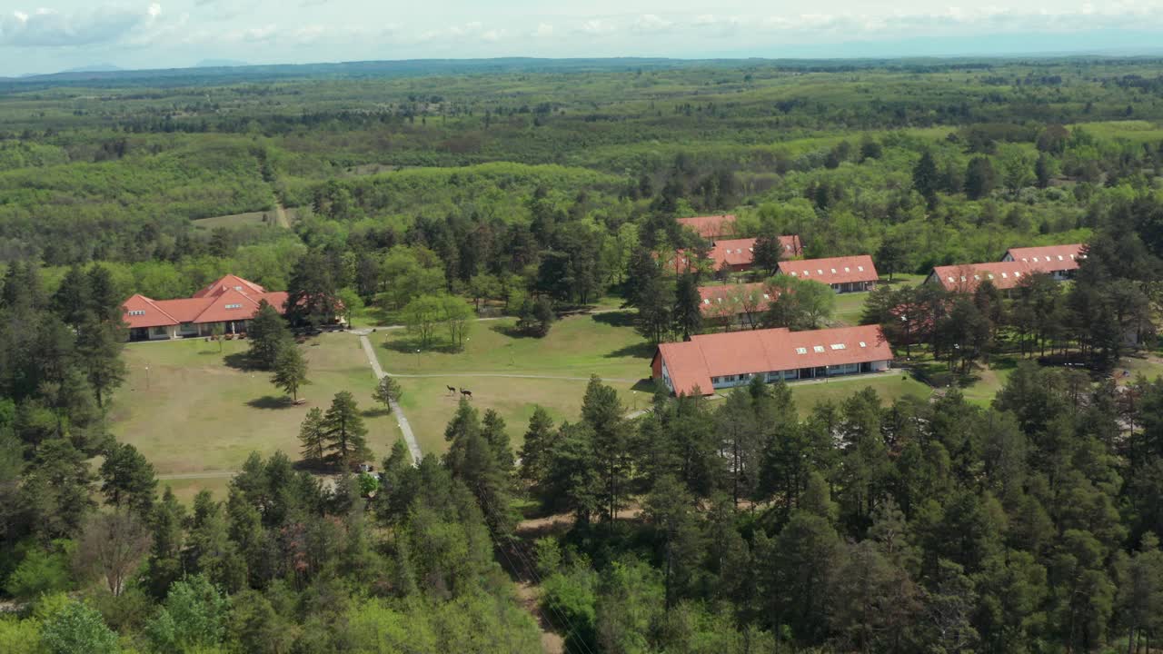 Aerial dolly pedestal shot pulling away from a resort tucked away in a forest