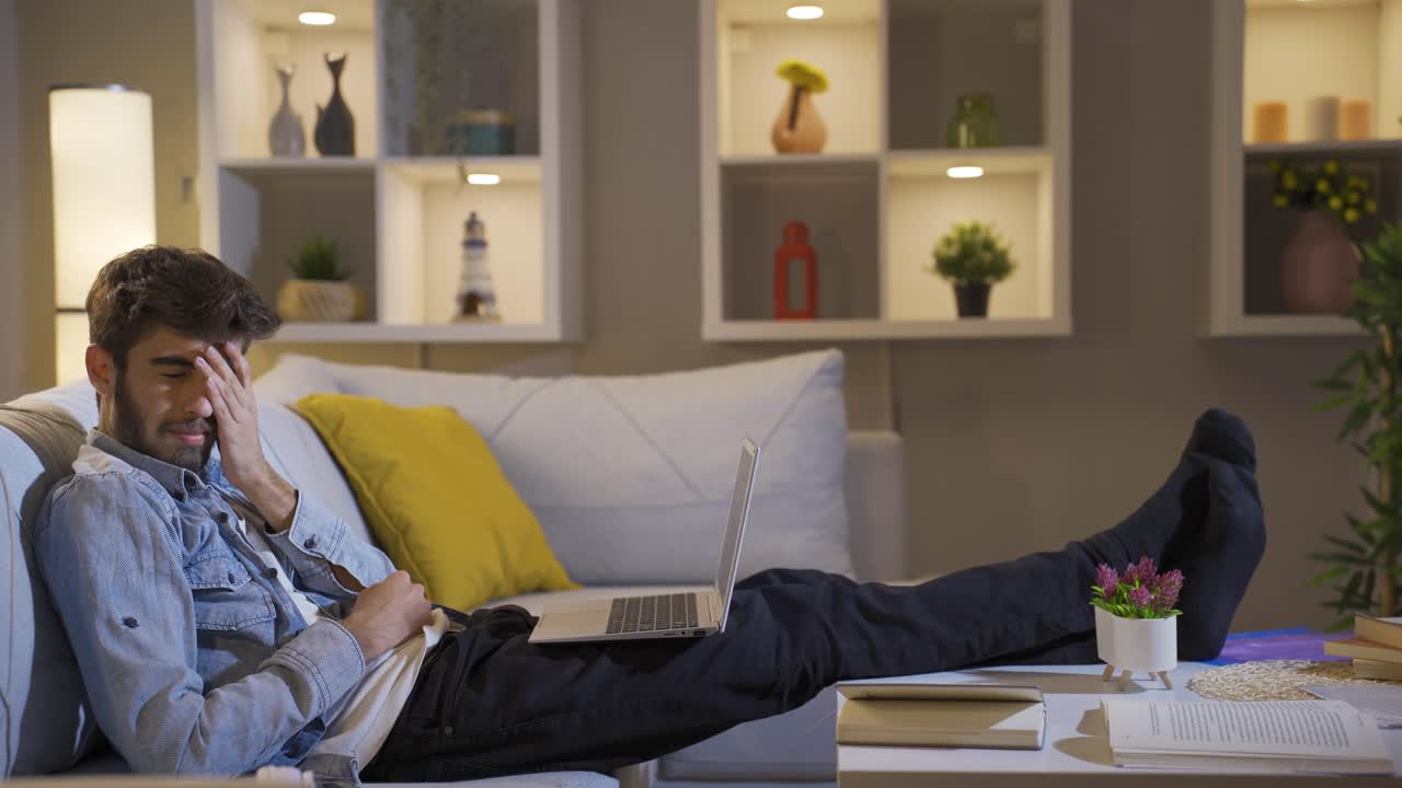 Man watching horror movie on laptop at night. The man is frightened and tense.