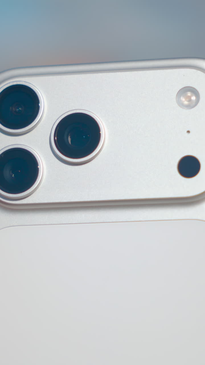 Close up of a hand holding a futuristic silver smartphone with a new triple lens camera system. Action