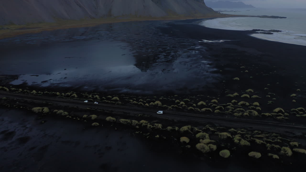 Aerial: Reveal shot of one car driving in Stokksnes of Iceland during blue hour