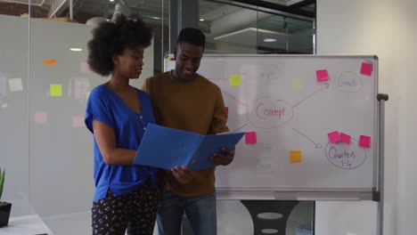 African-american-male-and-female-business-colleagues-analyzing-documents-in-meeting-room