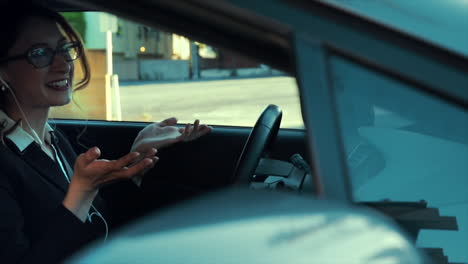 attractive caucasian business woman in a parked car while talking on the phone using her headphones