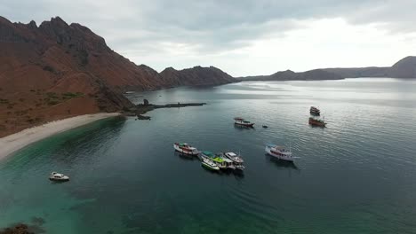 Aerial-view-of-boats-on-the-coast-of-the-Padar-island,-in-Komodo,-Indonesia---descending,-drone-shot