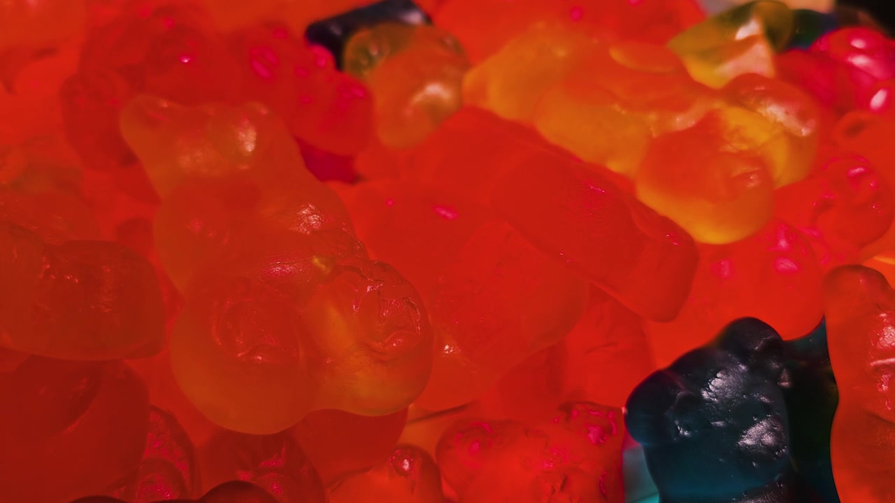 Orsetti gommosi colorati impilati in un espositore di caramelle self-service, con dolcetti di gelatina al gusto di frutta, riflessi tenui, profondità di campo ridotta e luminosa atmosfera da snack al dettaglio