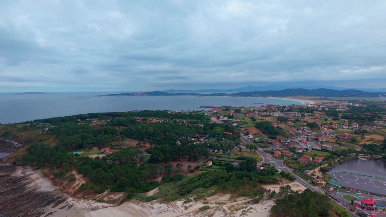 Droneilmakuva laajasta rannasta dyyneineen, vihreine kasvillisuuksineen ja kaupungista, josta on näkymä Lanzadan lahdelle Sanxenxossa Galiciassa, Espanjassa