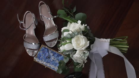 bridal arrangement featuring silver shoes, a white rose bouquet, and a delicate blue garter