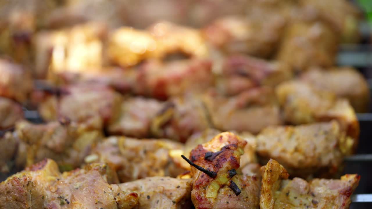 Barbecue in smoke. Meat on skewers cooking on the grill. Pork meat on the mangal in nature. Tasty shashlik cooking on the coals. Close-up.