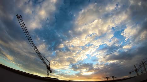 hermosa puesta de sol sobre grúas torre de construcción, lapso de tiempo