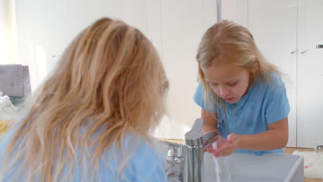 Girl-smiling-while-washing-face-in-sink