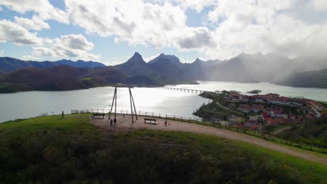 padres balanceando a su hijo en el columpio en el mirador en riaño, un pueblo en león, españa en la orilla de un gran embalse en las montañas cantábricas