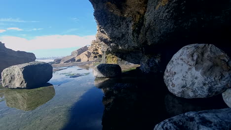 pequeñas gotas que caen de las cuevas formadas por el mar en la ladera de la colina, forman un pequeño espejo de agua contra el cielo azul