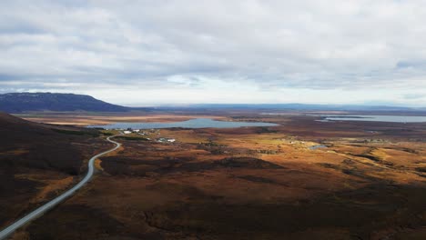 beautiful aerial of icelandic countryside with a lake in the distance and a long road running into a small town