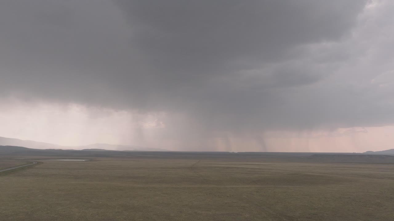 las lluvias en la lejanía barren una vasta llanura bajo pesadas nubes grises.