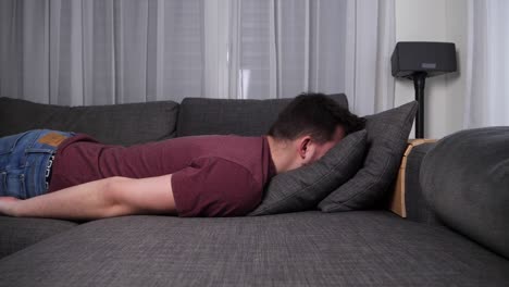 exhausted, tired man collapsing and face-planting onto couch pillow