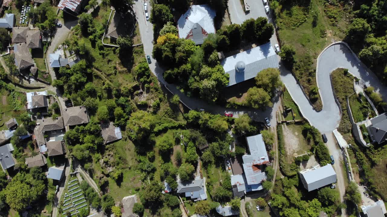 회색 돌 지붕이 있는 나무와 집이 있는 경사면에 있는 알바니아의 다다 산 마을