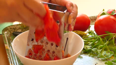 detail of female hand grated tomato for preparation of typical valencian paella