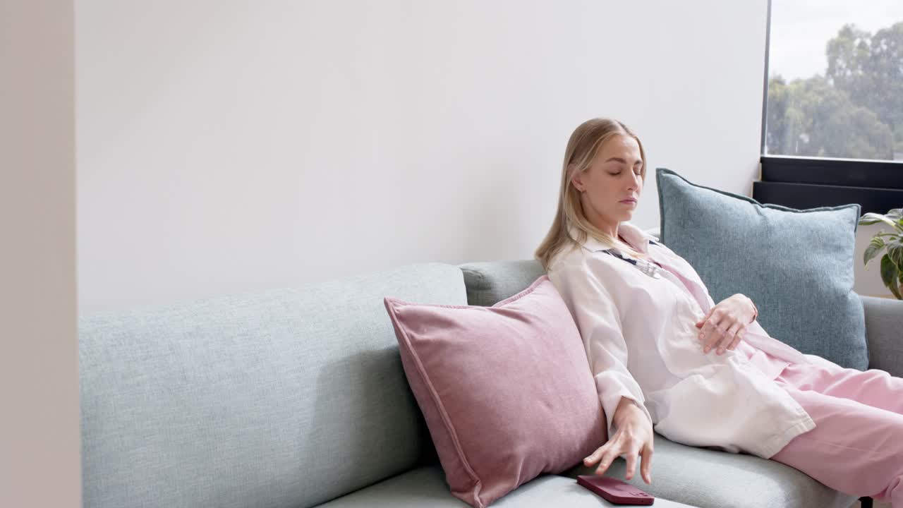 Adult woman holding red phone, scrolling, placing it, leaning back and relaxing on sofa, copy space
