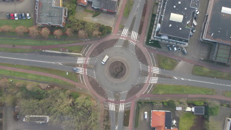 top down aerial of van and car entering roundabout - drone slowly descending