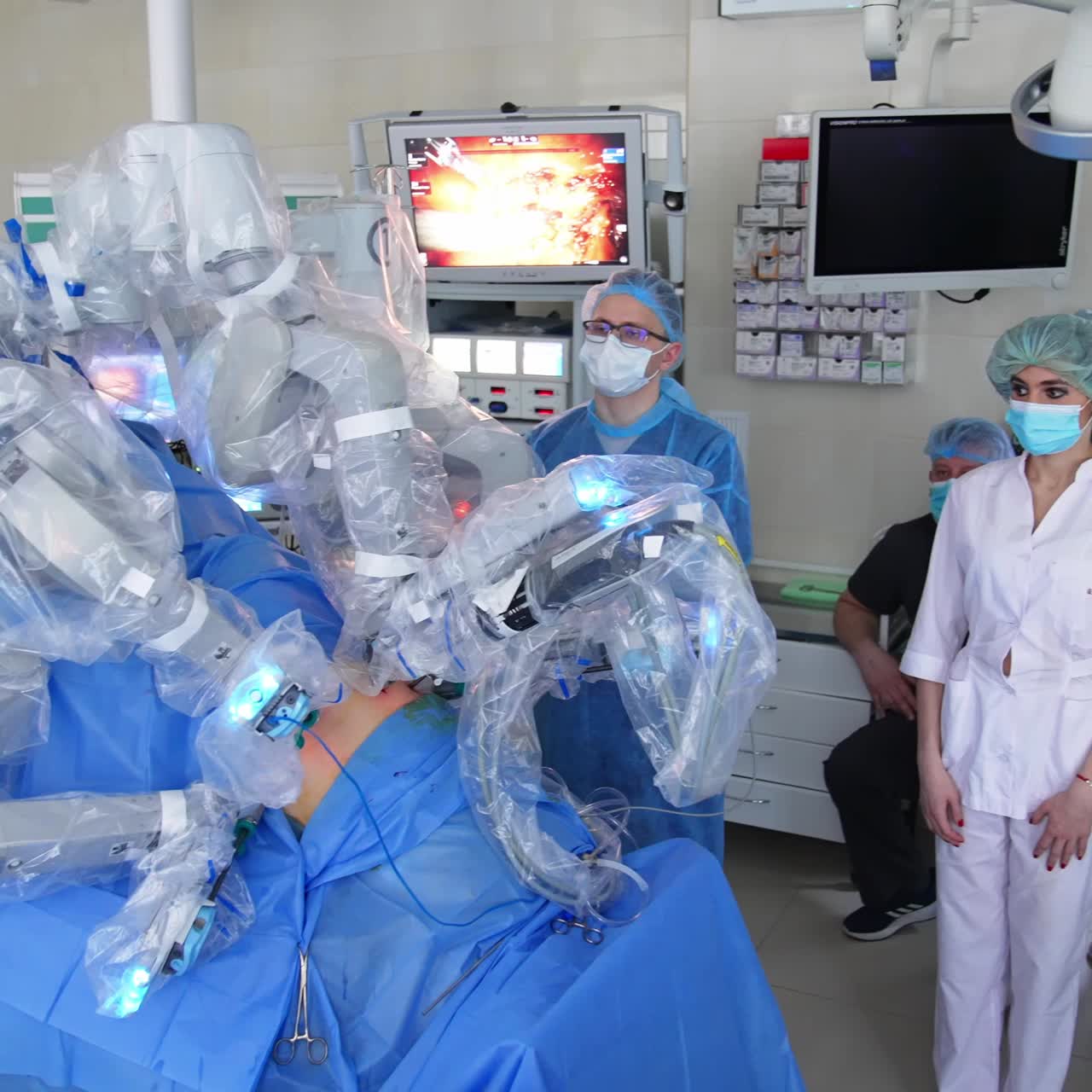Hospital medical staff gathered in surgery room to follow the work of futuristic equipment. Surgery operation conducted by Da Vinci robot surgeon