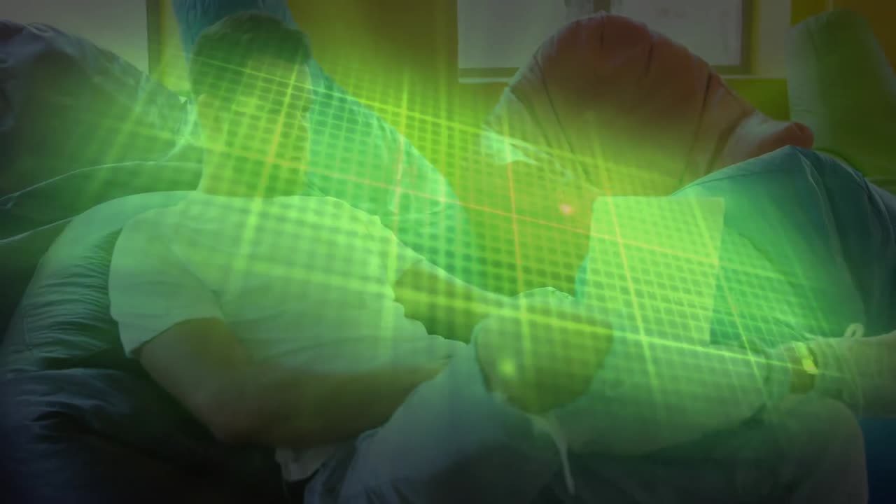 monitor de frecuencia cardíaca verde brillante contra hombre caucásico usando una computadora portátil sentado en una bolsa de frijoles en casa