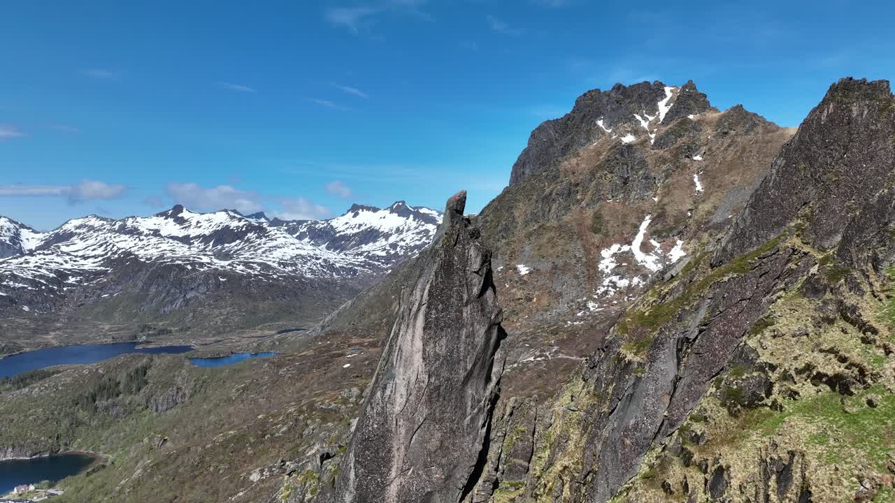 Svolvaergeita peak in Lofoten in slow ascending aerial with snowy spring mountains behind