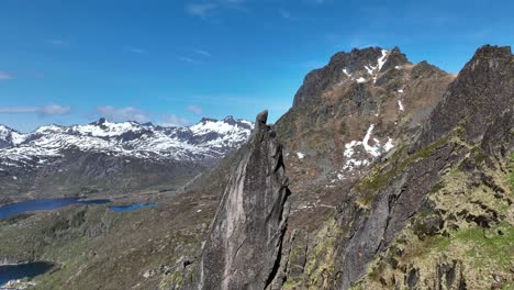 svolvaergeita peak in lofoten in slow ascending aerial with snowy spring mountains behind
