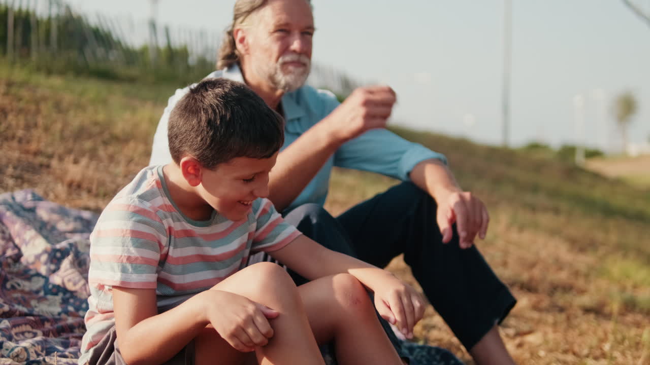 Nonno e nipote seduti a parlare all'aperto in una giornata di sole