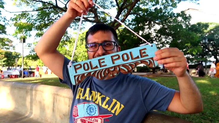 Happy tourist man showing an African wooden handmade sign that puts Pole Pole which means Slowly Slowly in Zanzibar