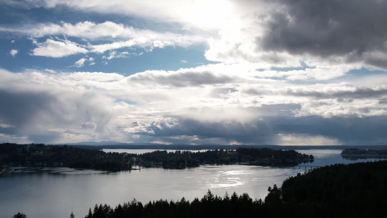 las dramáticas nubes rodantes reflejan el sol de la tarde en la prístina, puget sound, washington, hiperlapso aéreo