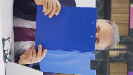 video vertical de un viejo hombre de negocios alegre trabajando en archivos.