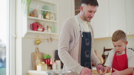el niño ayuda a papá a amasar la masa para las galletas de pan de jengibre.