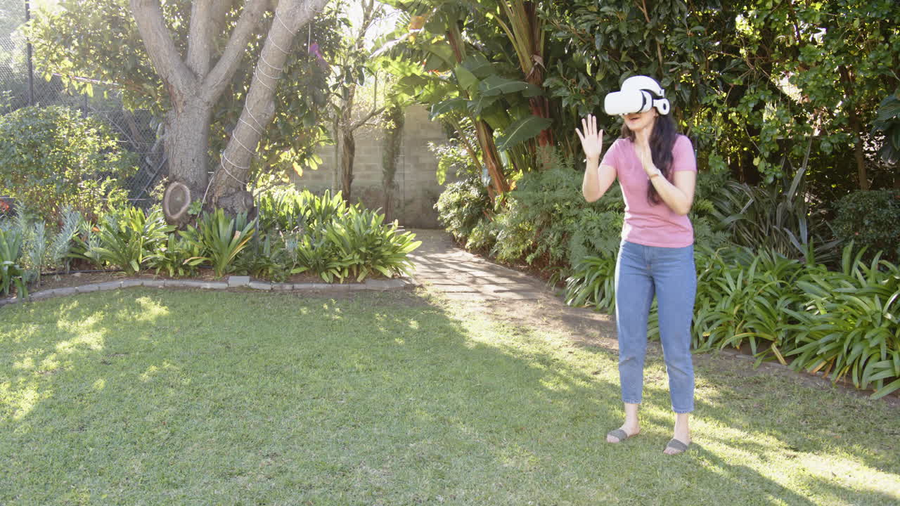 Using VR headset, woman enjoying virtual reality experience in garden