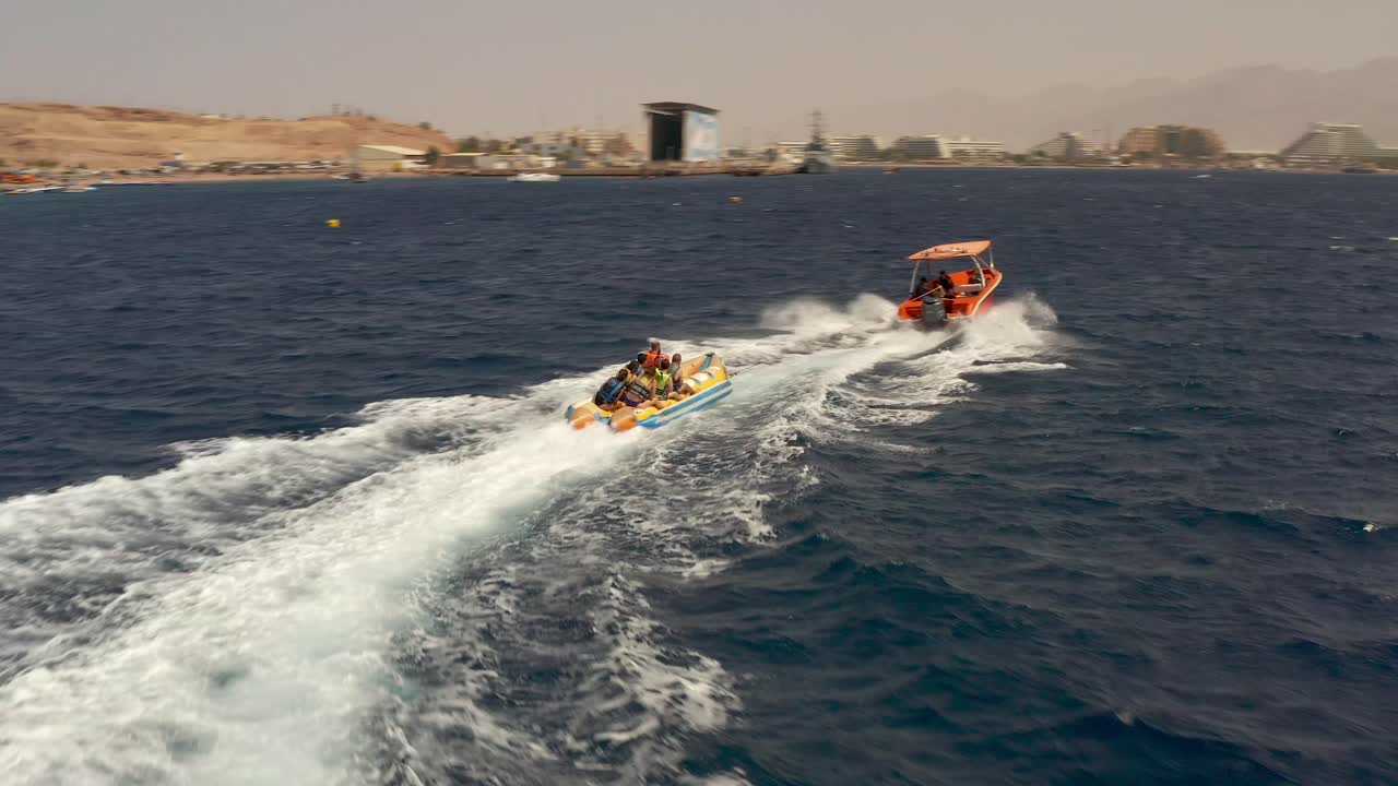 은 바다 에서 스피드 보트 가 끌고 있는 바나나 보트 에서 물 스포츠 를 즐기는 사람 들