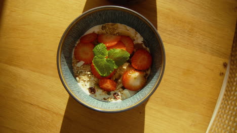 yogur de primera con granola casera y fresas decoradas con menta en un hermoso tazón