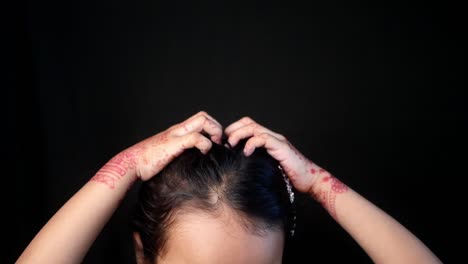 woman with henna on her hands putting her hair up in a bun