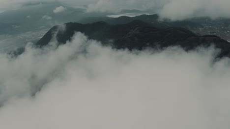 Drone-aerial-view-flying-high-over-clouds-revealing-beautiful-landscape-with-mountains