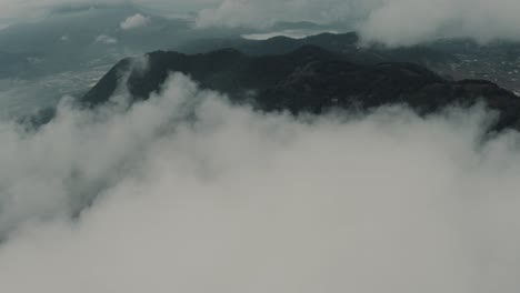 drone aerial view flying high over clouds revealing beautiful landscape with mountains