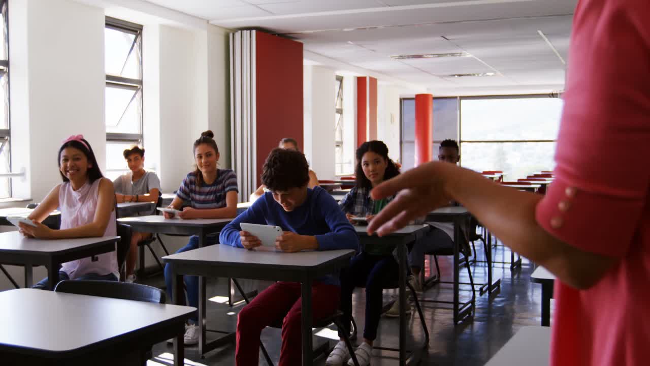 maestro que enseña a los estudiantes en una tableta digital en el aula