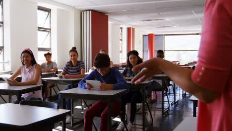 teacher teaching students on digital tablet in classroom